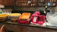 Glass punch bowl, ladle, and glasses alongside ceramic canisters and casserole dishes on kitchen counter