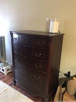 Front and side view of vintage wooden dresser with five curved drawers and metal handles, showing scratches and wear.