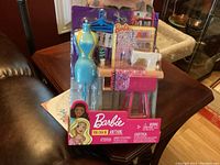 Playset in original packaging showing colorful Barbie sewing room items including dress mannequin and sewing machine