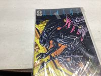Photo of comic book Aliens #1 showing front cover with black alien creature, protected with plastic cover.