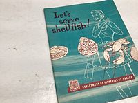 Front cover of the 'Let’s Serve Shellfish' cookbook from 1959, showing teal background with shellfish illustrations and woman drawing.