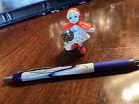 Front and side view of the small Little Red Riding Hood porcelain figurine measuring about pen length.
