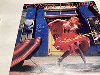Front of the album cover showing Cyndi Lauper in red dress against urban storefront background.
