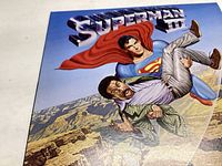 Front cover of Superman III soundtrack vinyl record album showing colorful illustrated artwork of Superman carrying a man.