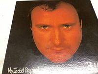 Front cover of Phil Collins No Jacket Required vinyl record showing close-up image of Phil Collins face in warm tones with album title.