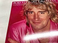 Front cover close-up of Rod Stewart in pink jacket with text "Rod Stewart Greatest Hits"