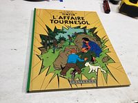 Front cover of Tin Tin 'L’affaire Tournesol' comic book showing main characters and title in yellow background.