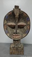 Front view of the African wooden tribal sculpture showing facial carvings and painted details.
