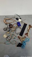 Overview of all jewelry items in lot - bracelets, necklaces, keychain, and chains visible
