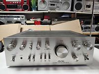 Front view of the Aurex SB-730 amplifier showing all control knobs, switches, and headphone jack. Power toggle switch turned on with a small red indicator light.