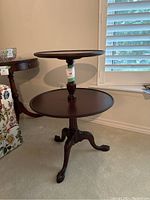 Full view of the George III mahogany dumbwaiter showing the two round shelves, central turned column, and three cabriole legs with claw feet.