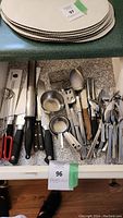 Top view of oval beige placemats stacked on countertop with a drawer below containing knives, measuring cups, and utensils.