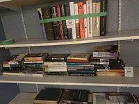 Full shelf showing assorted hardcover and paperback books including literary and religious titles.