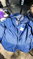 Blue Columbia men's jacket laid open on a table, showing the outer shell with a Columbia logo on chest.