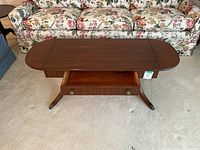 Full view of the drop leaf table with drawer open, showing wood finish and table shape.