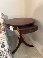 Front view of French round pedestal tripod table with one drawer open showing interior.