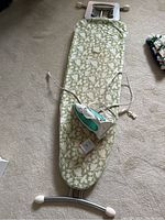 Full view of the ironing board with patterned cover and the iron placed on top