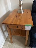 Wooden side table placed next to a sofa, showing the top surface and side profile with shelf below.