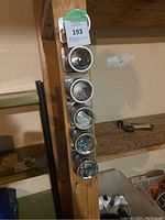 Full view of the magnetic organizer mounted vertically with six metal containers attached, showing some contents inside containers.