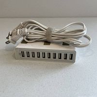 Front view of the white Anker USB charger showing 10 USB ports and attached power cord; visible signs of light use.