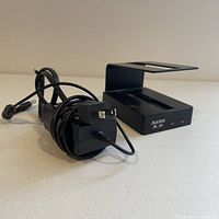 Front and side view of the black Kintec hard drive dock with power supply laid on a neutral surface.