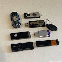 Top-down photo showing 7 external USB thumb drives with various designs and colors on a white surface.
