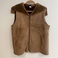 Tan brown suede style women's vest on hanger against plain white wall showing full front view.