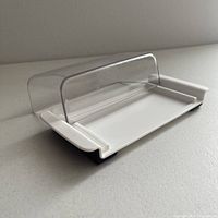 Front view of OXO butter dish tray with clear lid on white base, showing shape and materials.