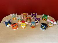 Group photo of 13 McDonald's Furby Gremlin character toys, front facing showing their faces, colors, and fur tufts selection.