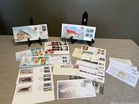 Photo showing 23 first day issue stamps in envelopes, with artwork and postmarks, mostly Canadian and 2 American stamps