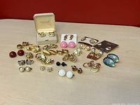 Overview of various gold-tone and colored bead stud earrings, including boxed items and carded pierced studs.