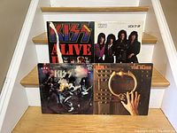 Four Kiss albums displayed on stairs: Alive!, Alive II, Music from The Elder, and Lick It Up.