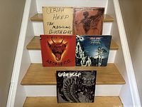 Five Uriah Heep vinyl LP albums shown standing on stairs. Includes The Magician's Birthday with homemade dust jacket, Abominog, and others.