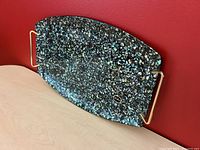 Photo showing full view of paua shell serving tray with brass handles against red background.