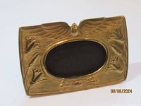 Front angled view showing gold tone frame with winged scarab and papyrus flowers decoration.