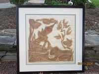 Full view of framed Thai temple rubbing artwork showing the entire scene and frame with natural outdoor background