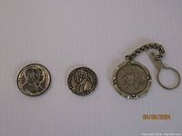 Three items side by side - two coins and one keychain with round coin charm