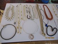 Multiple necklaces laid flat including faux pearls, chains, cord and bead strands
