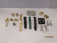 Full overview of all earrings, watch bands, ring, and brooch on white surface.