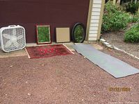 Wide shot showing all items including Bokara rug, two mirrors, peg board, lotus mat, and Lasko fan arranged on ground.