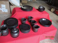 Full view of the 32 pieces arranged on a red surface showing dinner plates, salad plates, bowls, mugs, creamer, and sugar bowl.