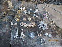 Full layout of the vintage rhinestone and crystal jewelry including earrings, brooches, necklace and bracelet on stone background.