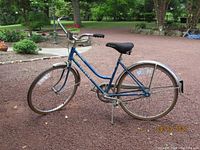 Full side view of the blue step-through frame bicycle with visible features including saddle, rear rack, and front and rear fenders.