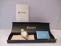 Stauer ladies watch displayed in original black box with documentation booklet behind.