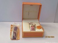 Stuhrling wristwatch in original box next to an additional pink leather strap in a plastic bag.