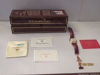 Original brown presentation box with pillow insert, watch, documentation and cleaning cloth laid out