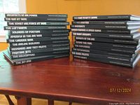 Photo showing all 23 volumes stacked with spines visible revealing the titles of each book in the collection.