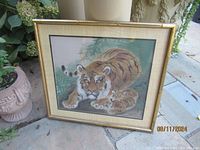 Full front view of framed silk painting showing mother tiger with cubs lying on ground, signed, set against beige and green background.