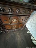 Close-up of carved wooden night stand showing floral carvings and drawer details
