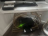 White rectangular console table with faux marble top and gold circular metal frame base shown with a TV and electronic devices beneath.